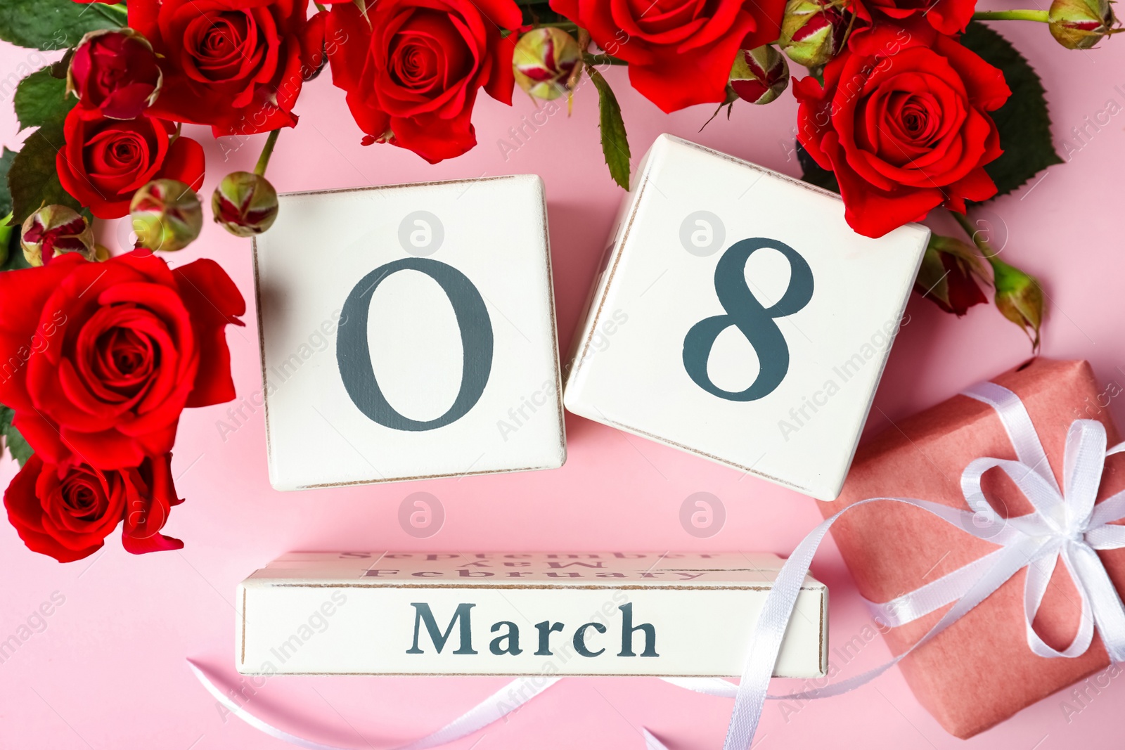 Photo of Wooden block calendar with date 8th of March, gift and roses on pink background, flat lay. International Women's Day