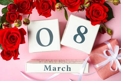Photo of Wooden block calendar with date 8th of March, gift and roses on pink background, flat lay. International Women's Day