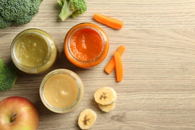 Photo of Tasty baby food in jars and ingredients on light wooden table, flat lay. Space for text