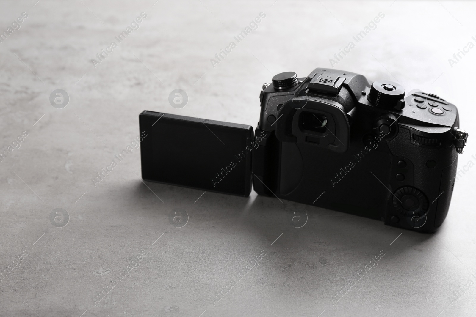 Photo of Modern camera on light grey stone table. Video production industry