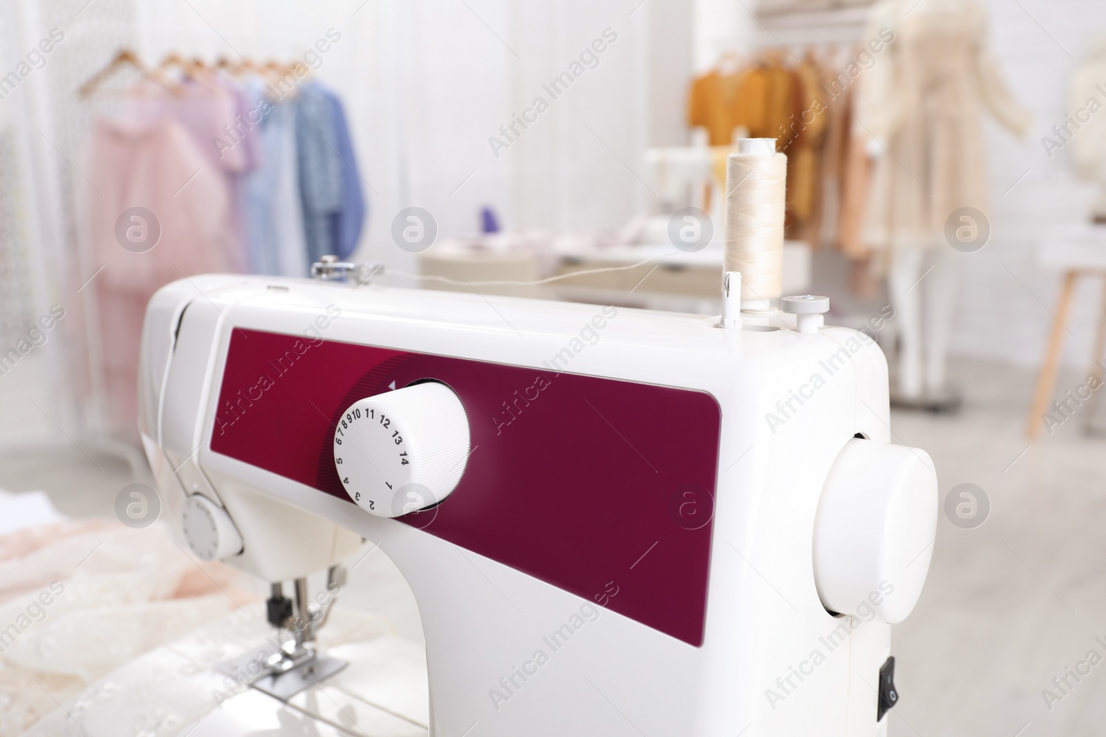 Photo of Modern sewing machine in dressmaking workshop, closeup