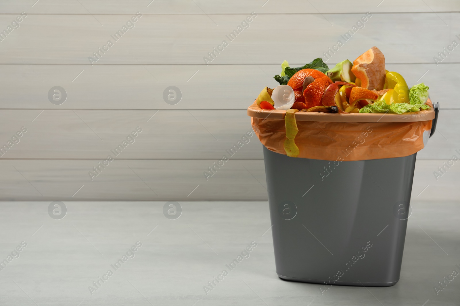 Photo of Trash bin with natural garbage on light background, space for text. Composting of organic waste