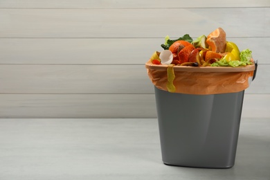 Trash bin with natural garbage on light background, space for text. Composting of organic waste