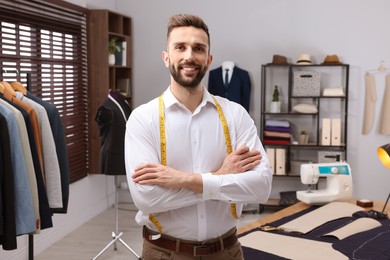 Photo of Happy dressmaker with measuring tape in workshop