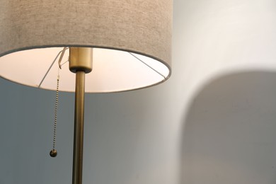 Photo of Stylish lamp near light wall, closeup. Space for text
