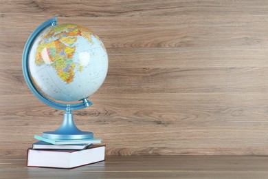 Globe and books on wooden table, space for text. Geography lesson