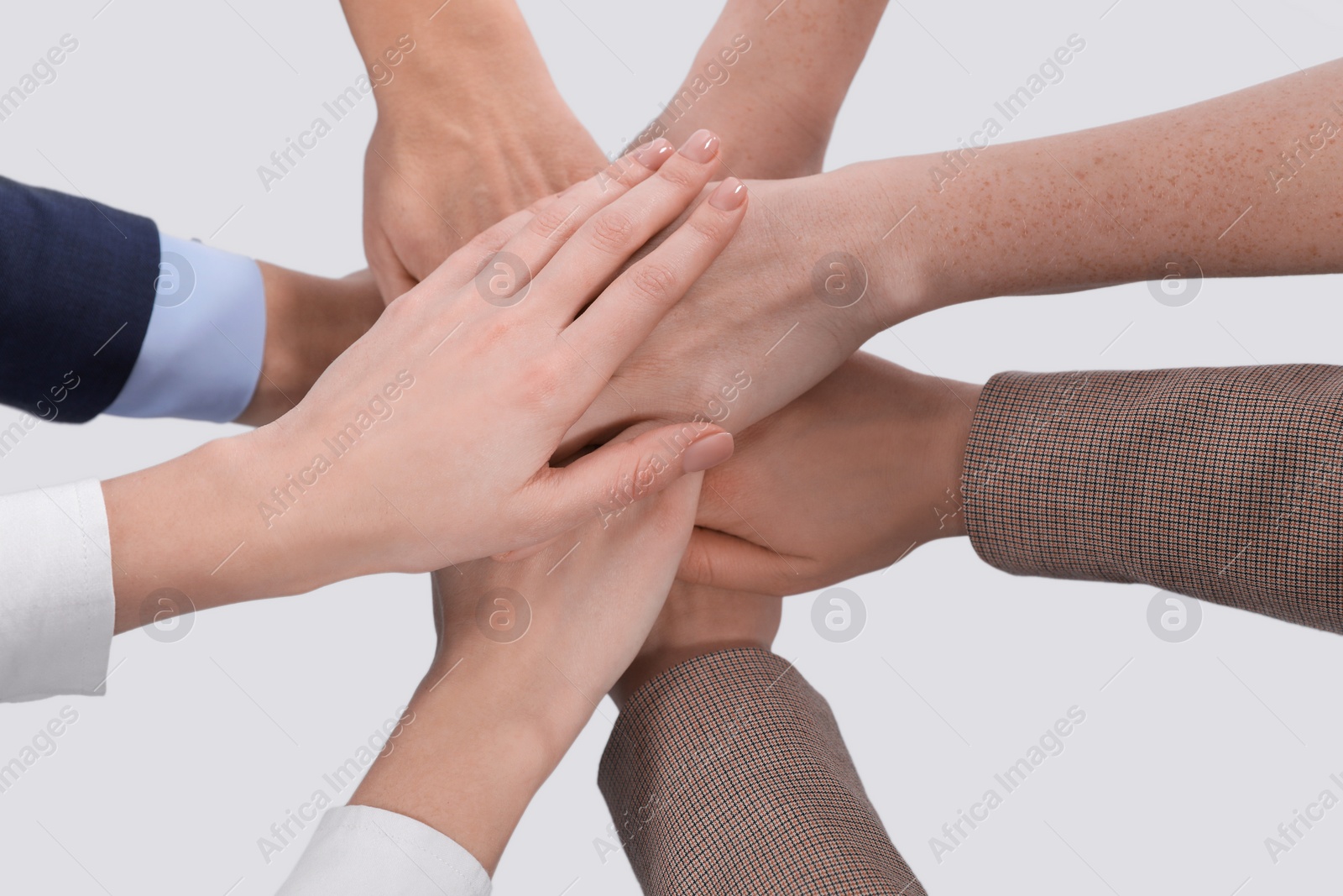 Photo of Women holding hands together on light background, closeup