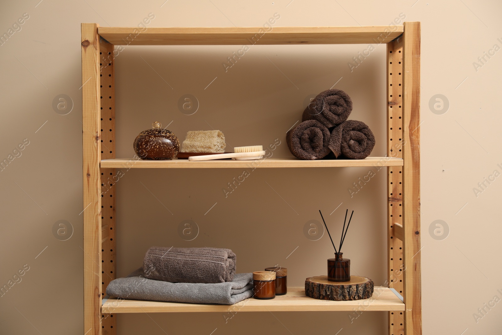 Photo of Soft towels, candles, air freshener and spa products on shelves indoors