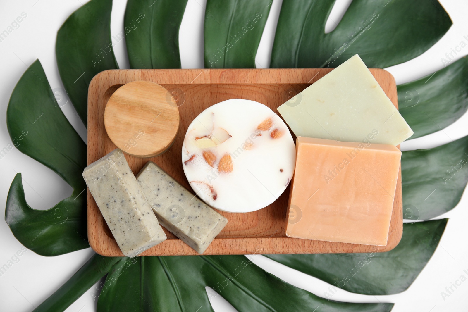 Photo of Wooden tray with eco friendly personal care products on green leaf, top view