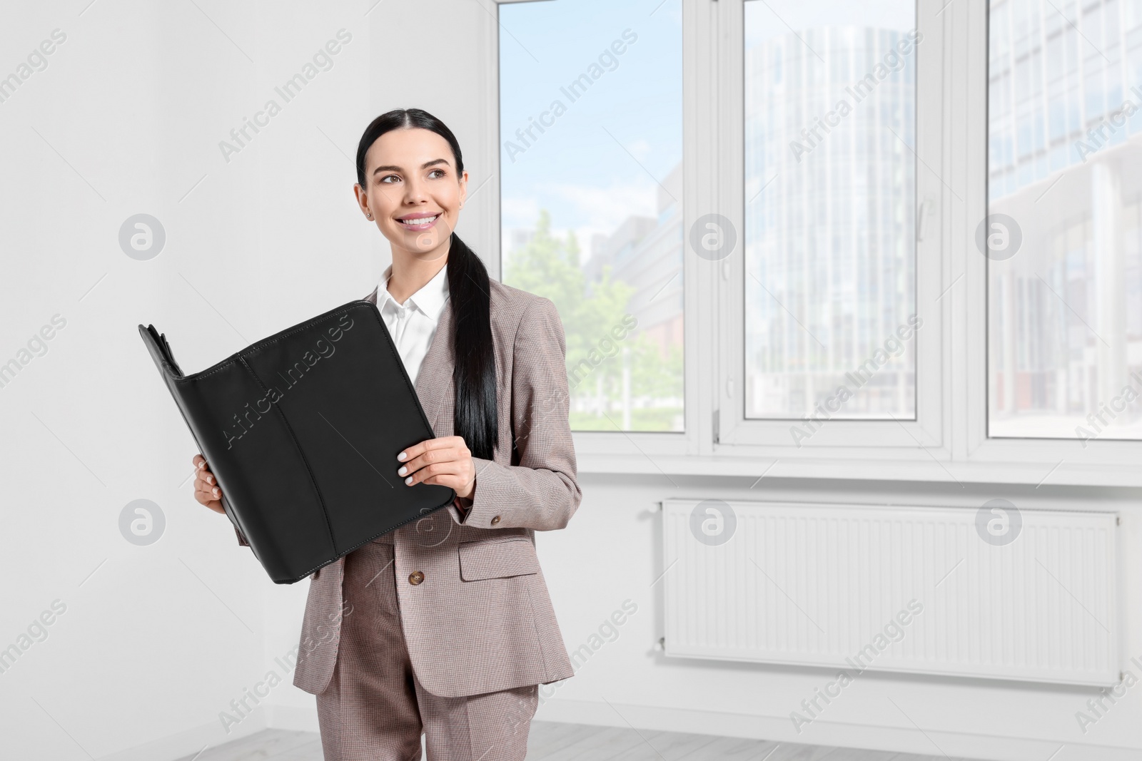 Photo of Beautiful real estate agent with documents indoors, space for text