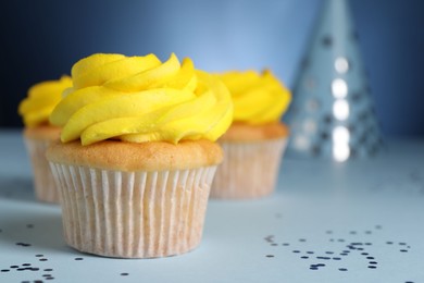 Delicious cupcakes with bright cream and confetti on blue background, closeup