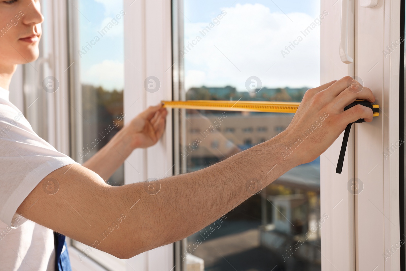 Photo of Worker measuring plastic window indoors, closeup. Installation process