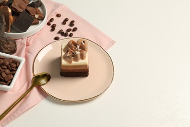Photo of Piece of triple chocolate mousse cake, ingredients and spoon on white table, space for text