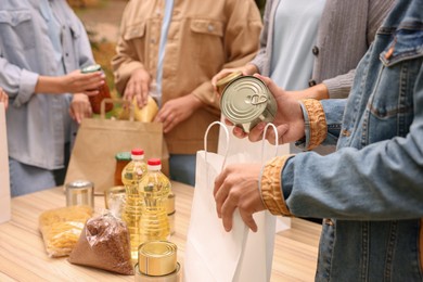 Group of volunteers packing food products at table outdoors, closeup