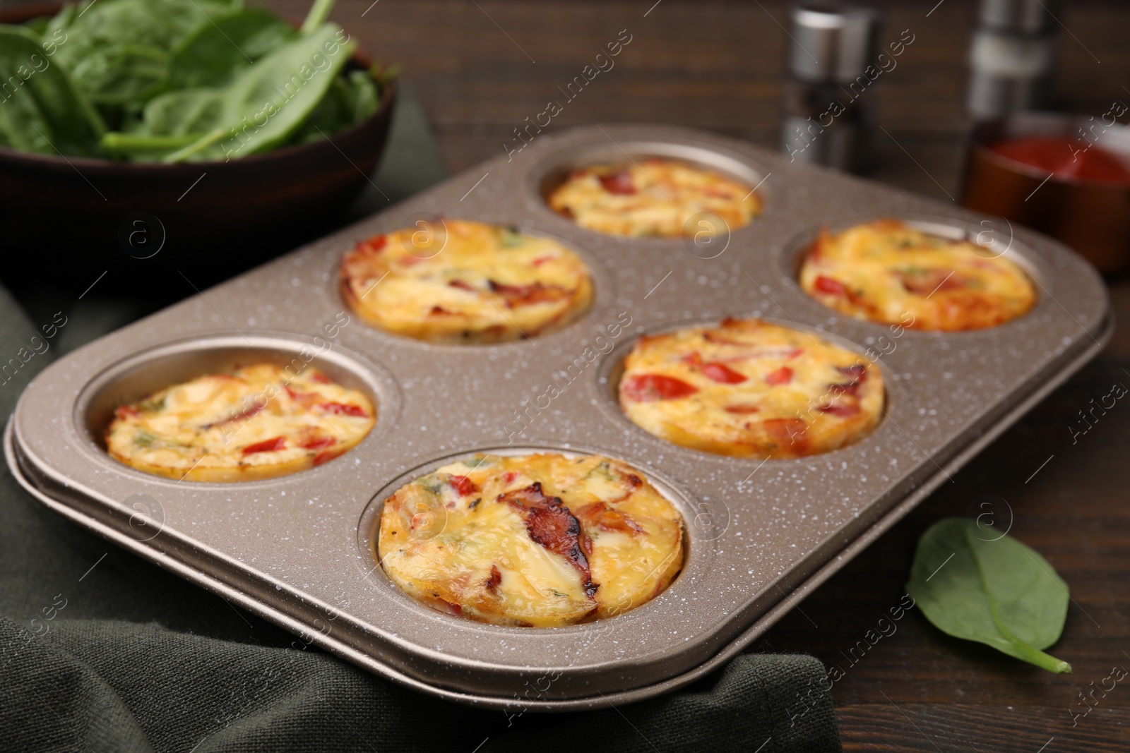 Photo of Freshly baked bacon and egg muffins with cheese in tin on table, closeup