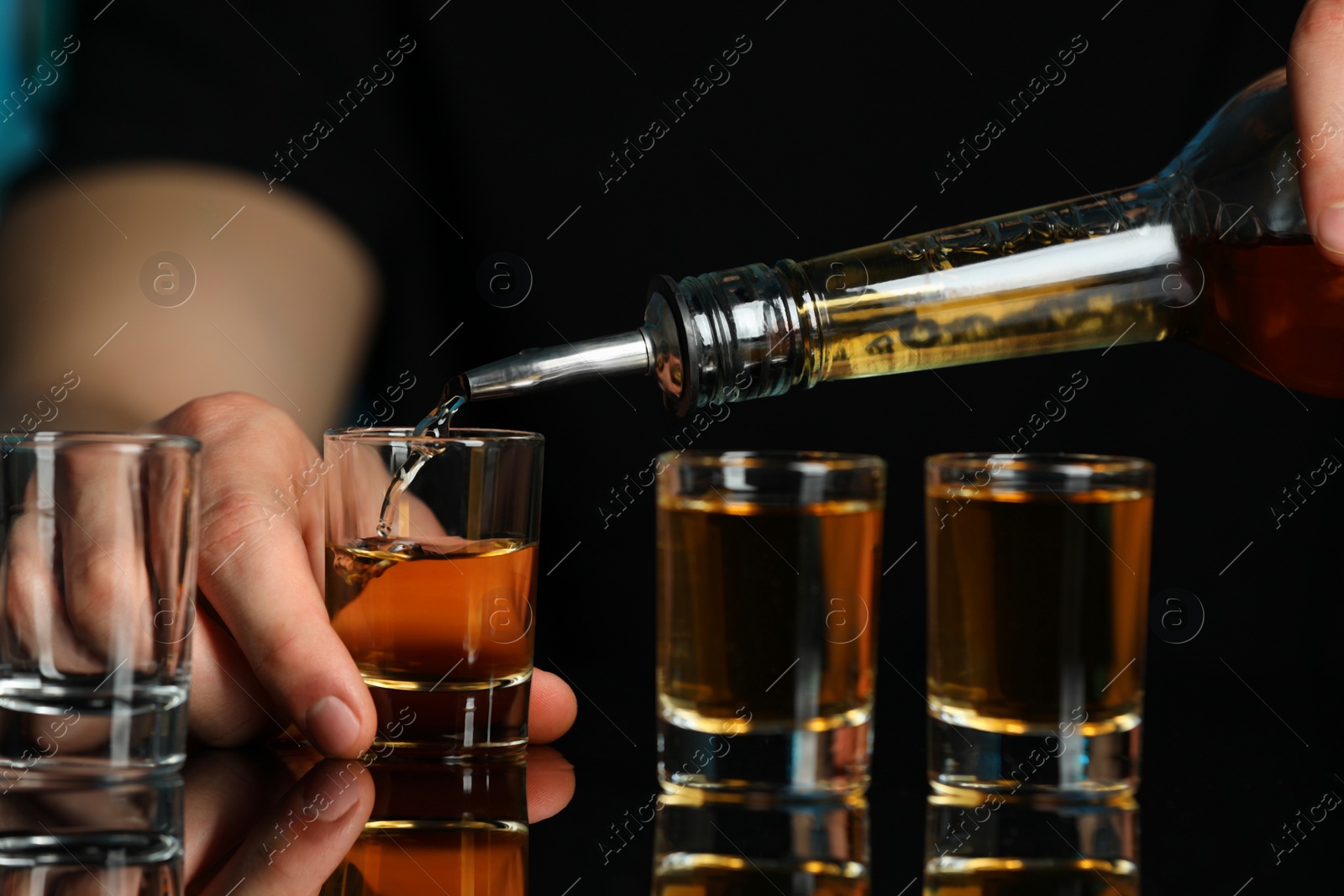 Photo of Bartender pouring alcohol drink into shot glass at mirror bar counter, closeup