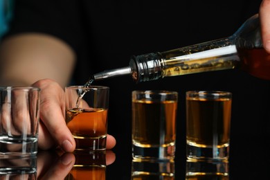 Bartender pouring alcohol drink into shot glass at mirror bar counter, closeup