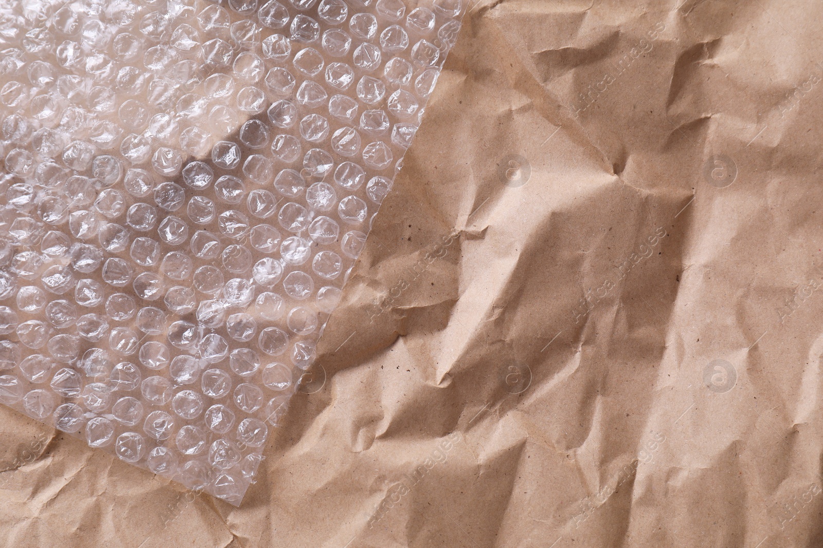 Photo of Transparent bubble wrap on kraft paper, top view. Space for text