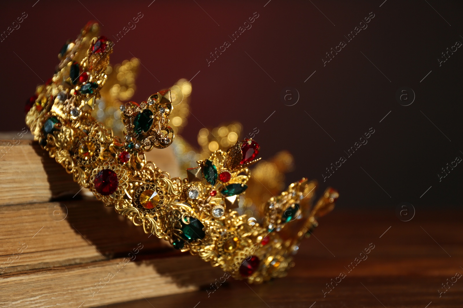 Photo of Beautiful golden crown and old books on wooden table. Fantasy item