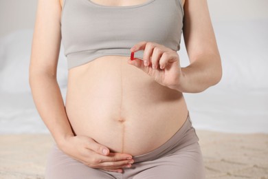 Photo of Pregnant woman taking pill on bed, closeup