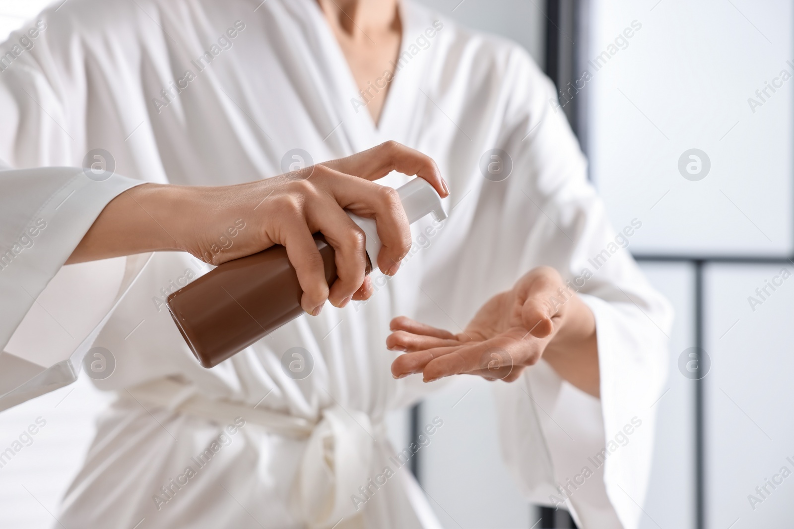 Photo of Woman applying self-tanning product onto hand indoors, closeup