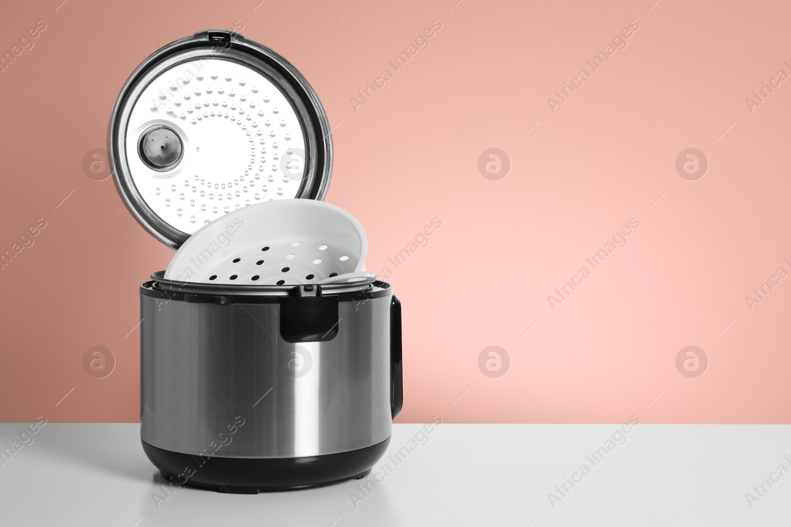 Photo of Modern electric multi cooker on table against color background. Space for text