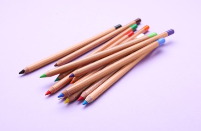 Photo of Many colorful pastel pencils on violet background. Drawing supplies
