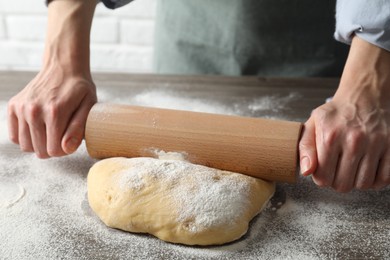 Photo of Woman rolling raw dough at table, closeup