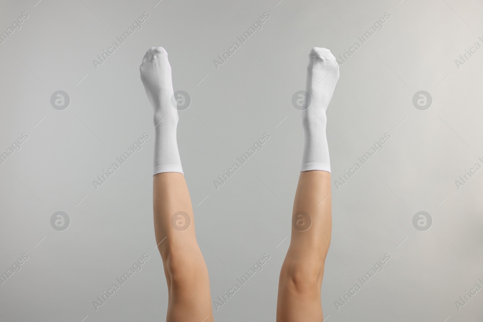 Photo of Woman in stylish white socks on light grey background, closeup