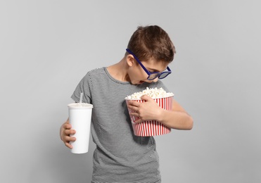 Photo of Boy with 3D glasses, popcorn and beverage during cinema show on grey background