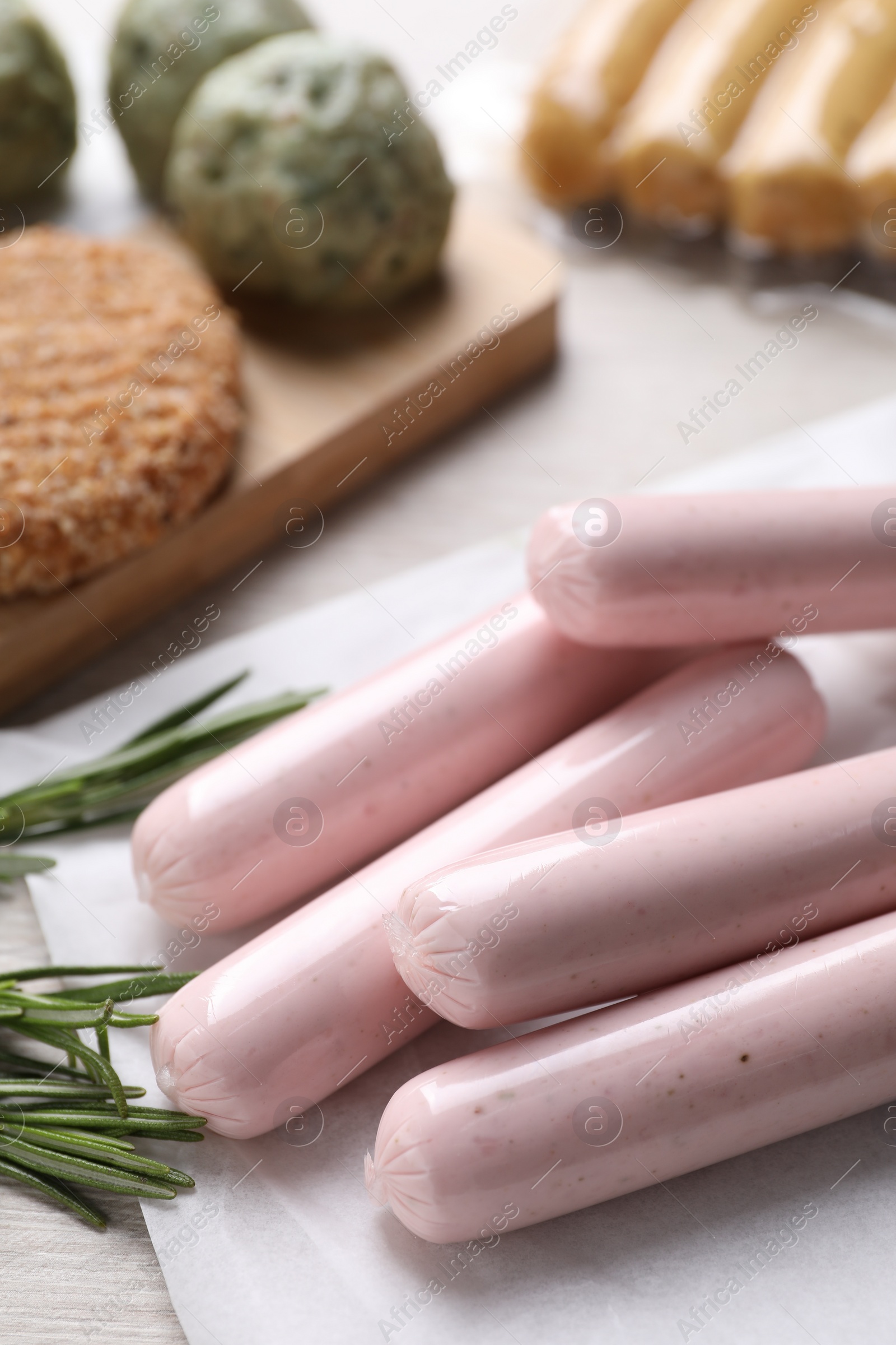 Photo of Vegan sausages and rosemary on white table, closeup