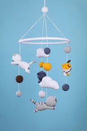Photo of Cute baby crib mobile on light blue background