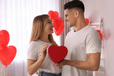 Photo of Lovely couple with gift in room. Valentine's day celebration