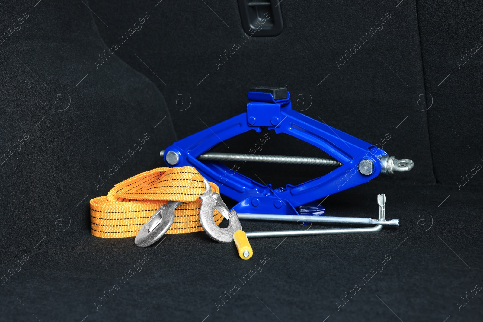 Photo of Scissor jack and towing strap in trunk. Car safety equipment