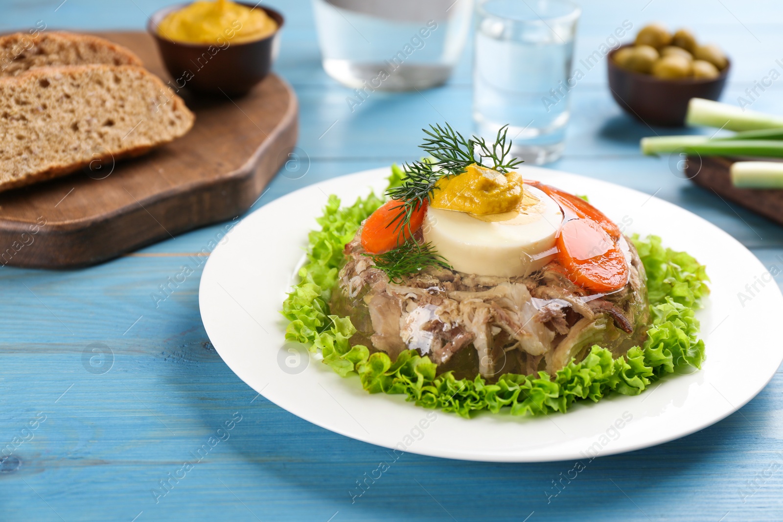 Photo of Delicious aspic with meat and vegetables served on light blue wooden table