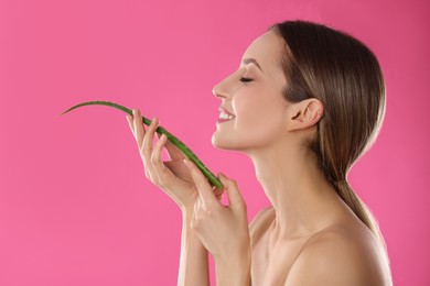Photo of Young woman with aloe leaf on pink background