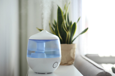 Photo of Modern air humidifier on table in living room. Space for text