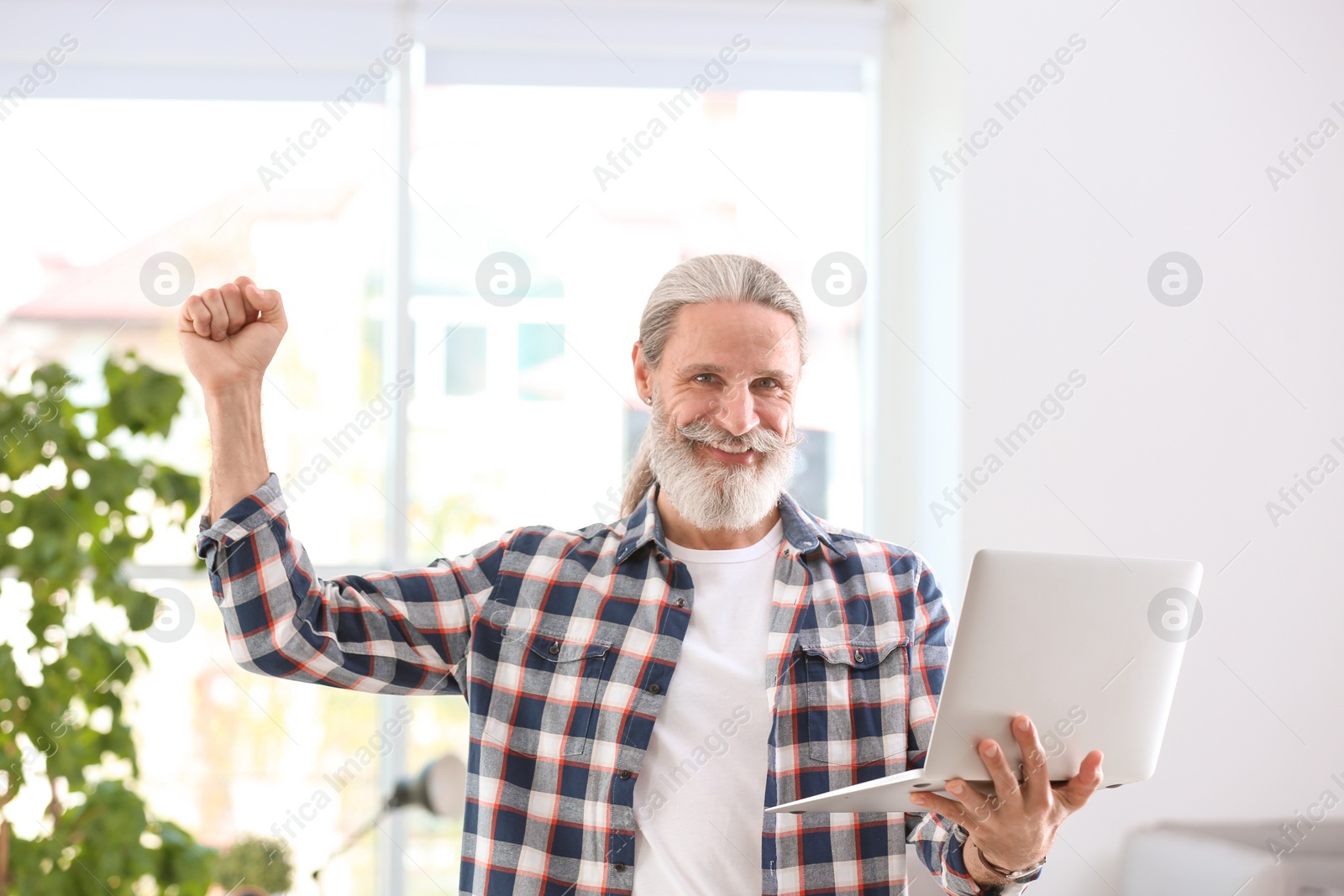 Photo of Portrait of handsome mature man in shirt with laptop, indoors