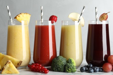 Photo of Glasses of delicious juices and fresh ingredients on white marble table