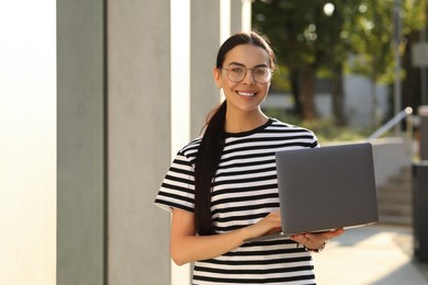 Happy young woman using modern laptop outdoors