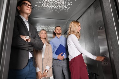 Group of office workers talking in modern elevator