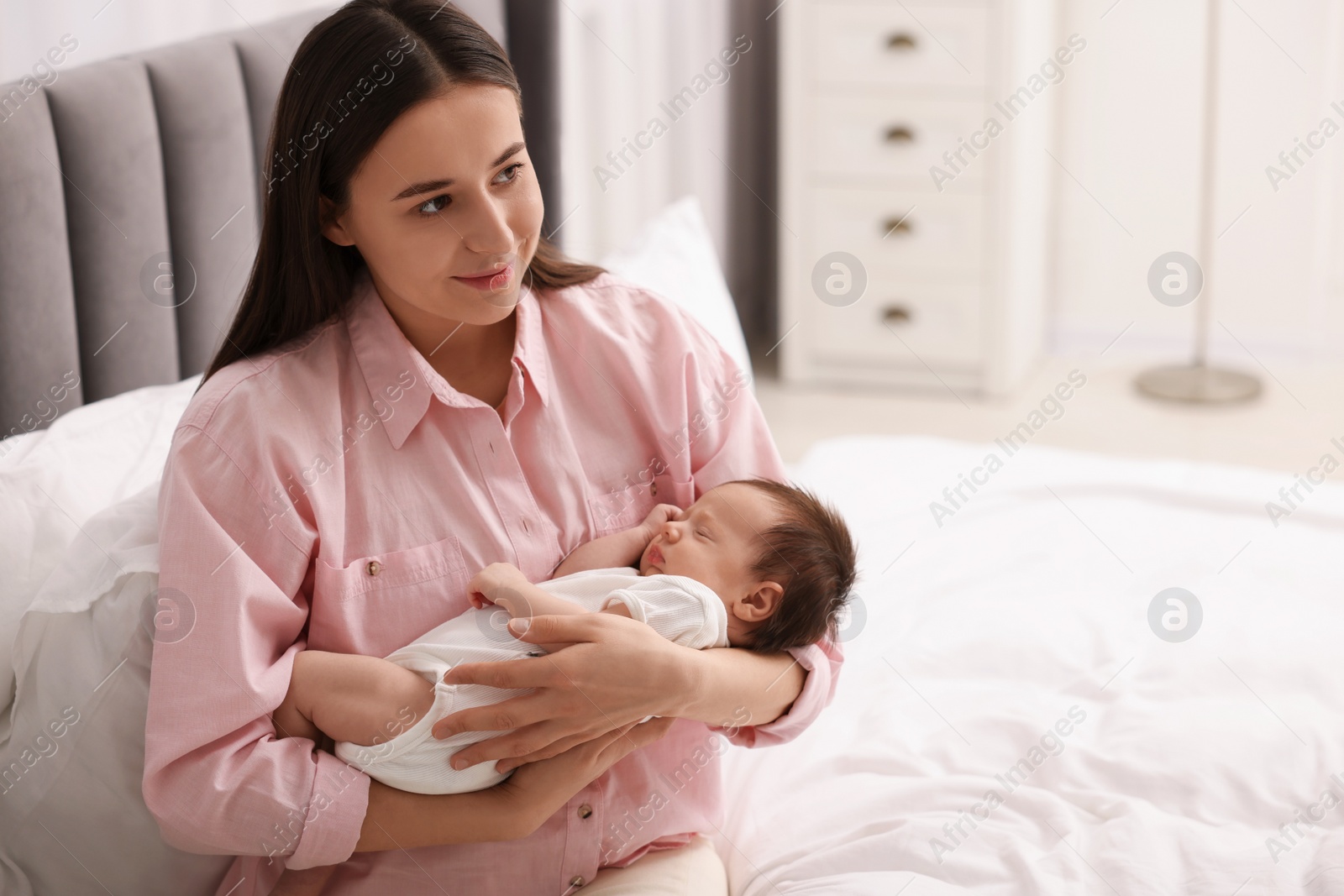 Photo of Mother with her sleeping newborn baby on bed at home