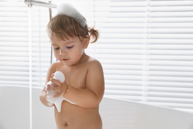 Photo of Cute little girl taking bubble bath indoors. Space for text