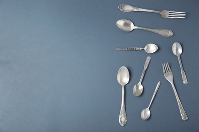 Photo of Set of silver cutlery on grey background, flat lay with space for text