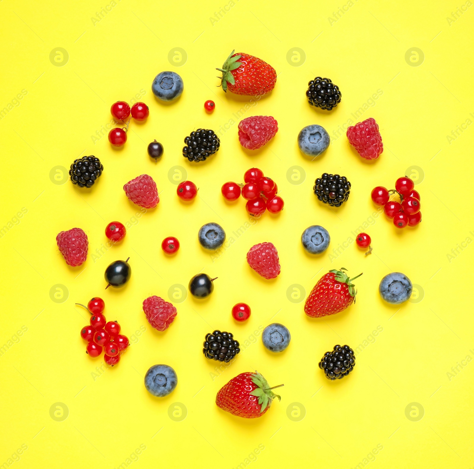 Photo of Different fresh berries on yellow background, top view