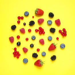 Photo of Different fresh berries on yellow background, top view