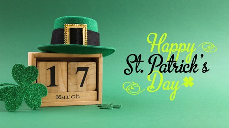 Image of Happy St. Patrick's day card. Wooden block calendar with date March 17, leprechaun hat and decorative clover leaves on green background