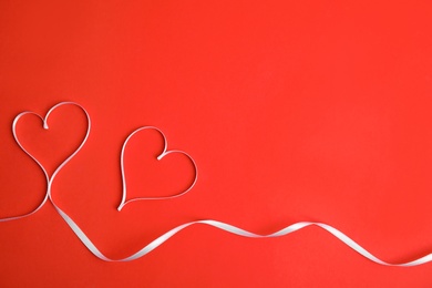 Photo of Hearts made of white ribbon on red background, flat lay with space for text. Valentine's day celebration