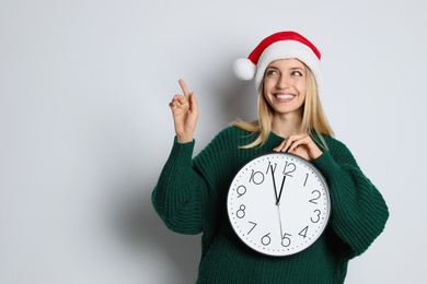 Photo of Woman in Santa hat with clock on white background, space for text. New Year countdown