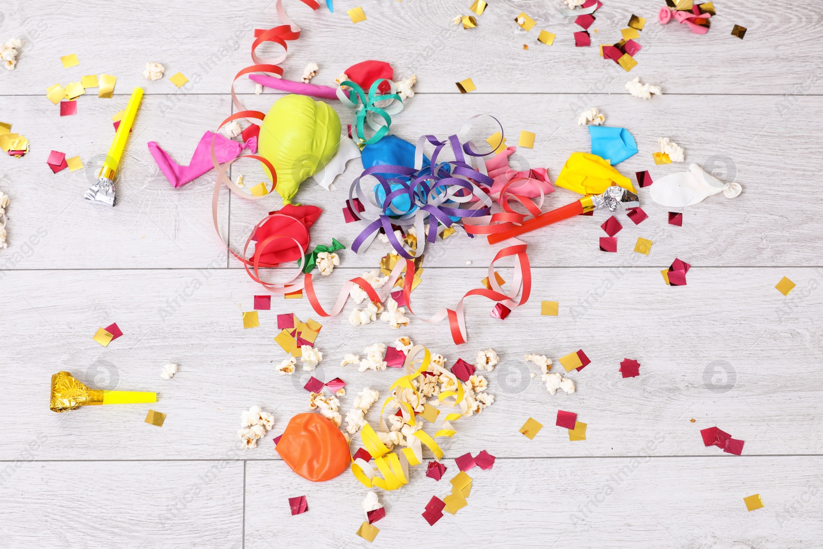 Photo of Messy floor with popcorn, streamers, confetti and used balloons after party, top view